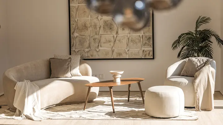 Sitzgruppe mit Bouclé-Sofa, Sessel und rundem Holztisch in einer Architektenwohnung