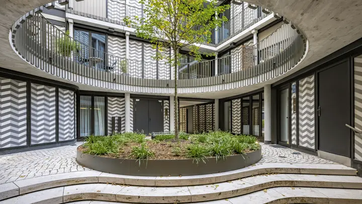 Runder Innenhof mit Baum und gemusterter Fassade