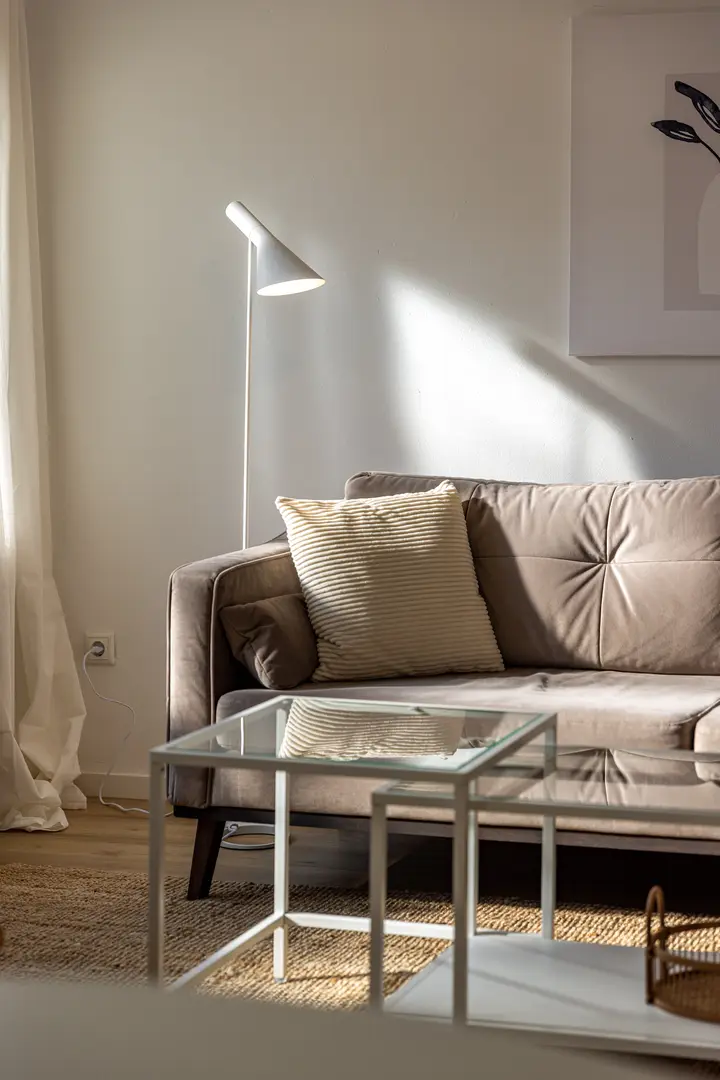Sofa mit Kissen und Glastisch im sanierten Wohnzimmer