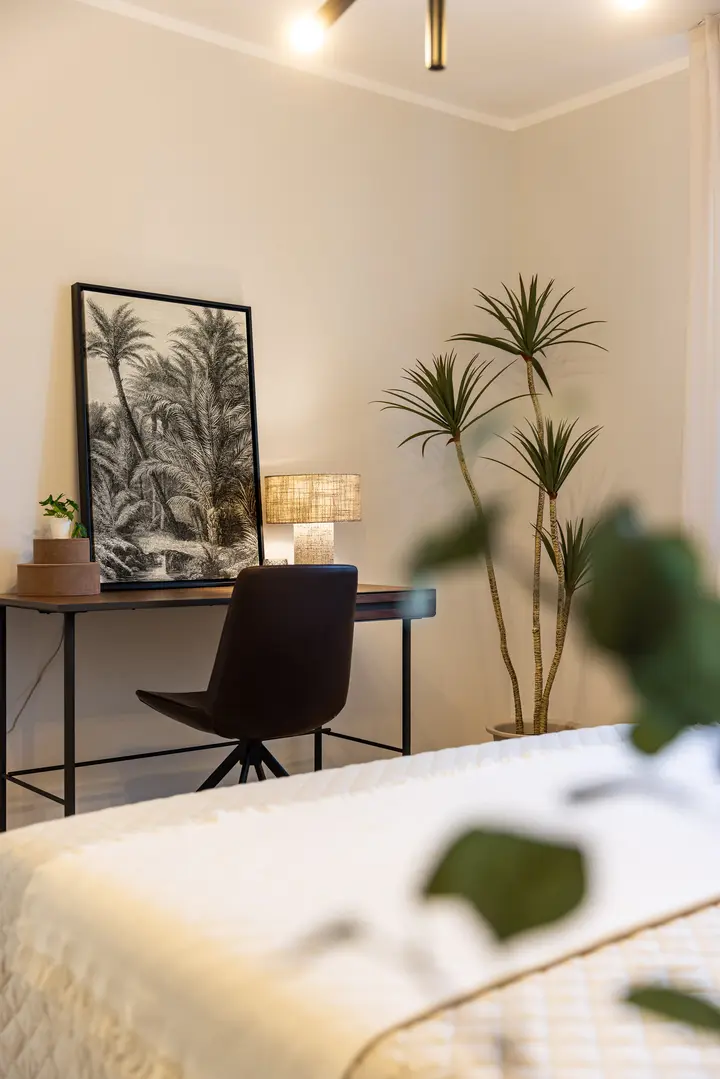 Arbeitsplatz mit Bild und Pflanze im Schlafzimmer