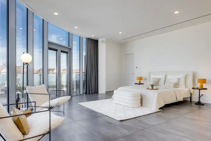 Schlafzimmer mit runder Glasfassade nach dem Home Staging einer Luxusimmobilie