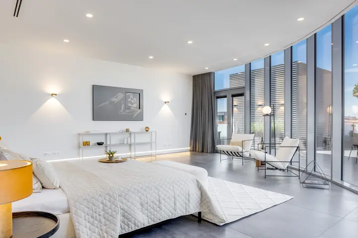 Schlafbereich mit Bett, Wandleuchten und Glasfront