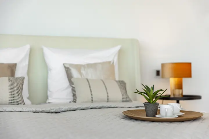 Bett mit Kissen, Tischleuchte und Tablett im Penthouse