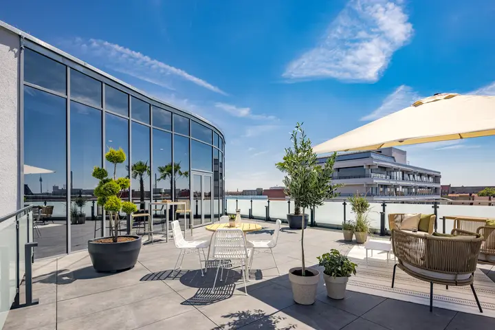 Dachterrasse mit Sonnenschirm, Pflanzen und Loungemöbeln