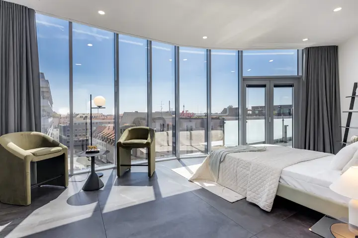 Schlafzimmer mit runder Fensterfront und Blick auf die Stadt