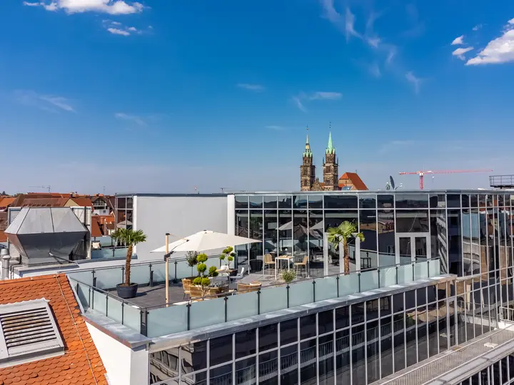 Dachterrasse mit Sonnenschirmen über den Dächern der Stadt