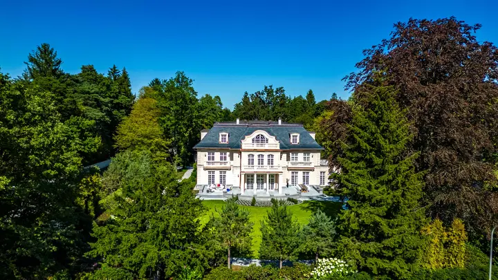 Villa mit weißer Fassade inmitten eines Parks