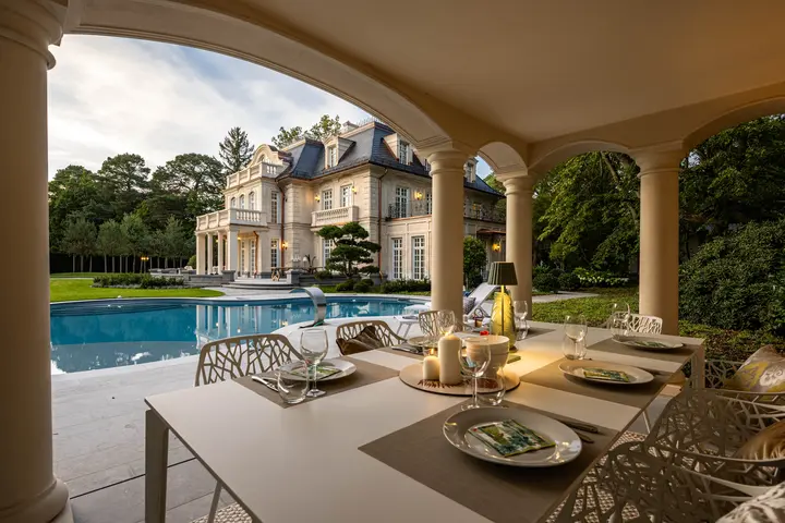 Gedeckter Tisch auf der Terrasse mit Blick auf Pool und Villa