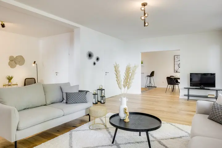 Wohnzimmer mit Sofa, rundem Couchtisch und Blick in den Essbereich