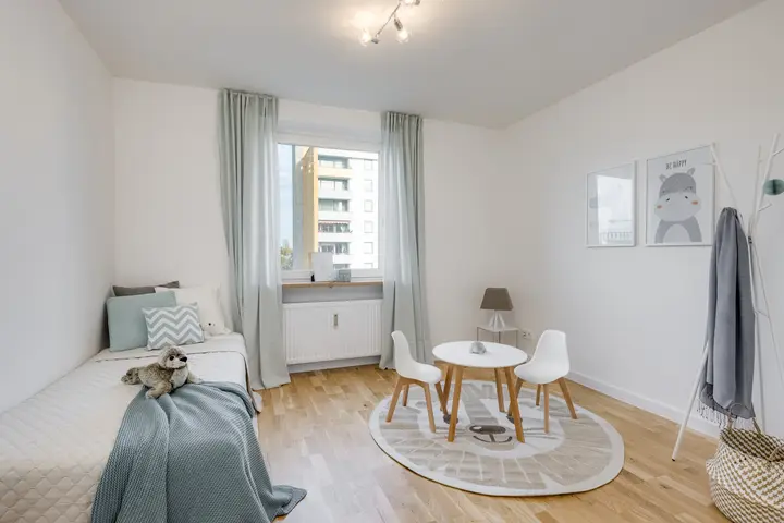 Kinderzimmer mit Bett, Kindertisch und rundem Teppich