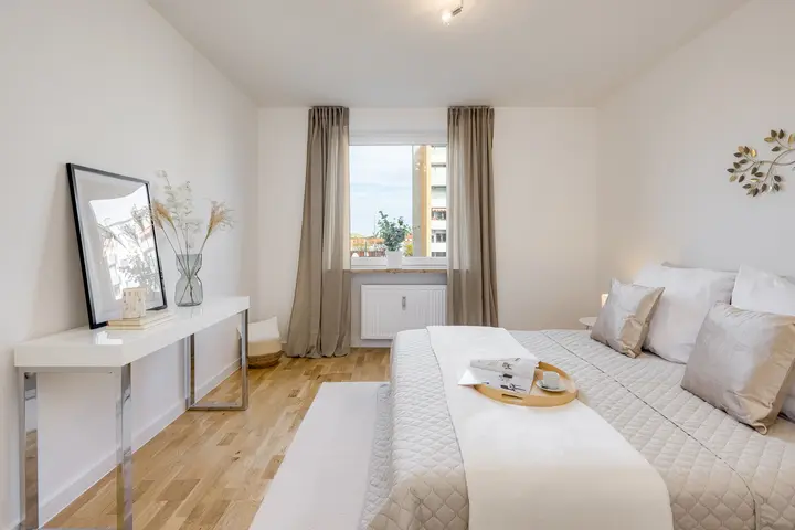Schlafzimmer mit Bett, Konsole und Vorhängen in einer Eigentumswohnung