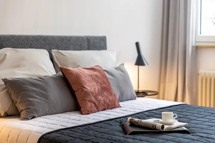 Bett mit grauem Kopfteil, Kissen und Tablett