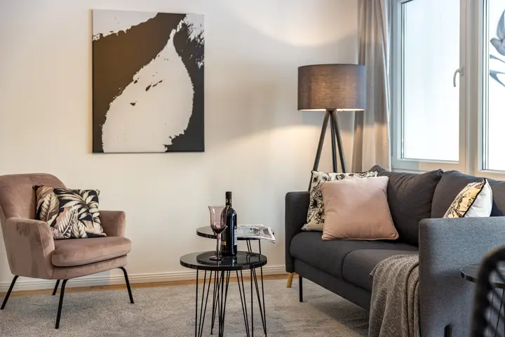 Wohnzimmer mit Sofa, Sessel und Stehleuchte nach dem Home Staging