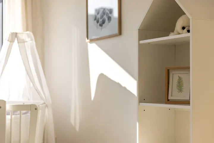 Kinderzimmer mit Babybett und Regal in Hausform