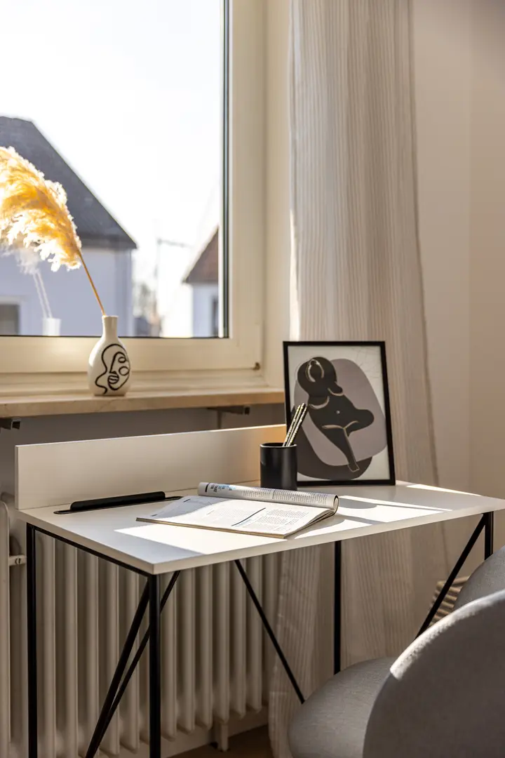 Arbeitsplatz am Fenster mit Schreibtisch und Bild