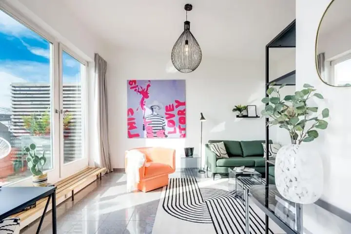 Wohnzimmer mit Pop-Art-Bild, Sessel und Sofa in einer hellen Wohnung