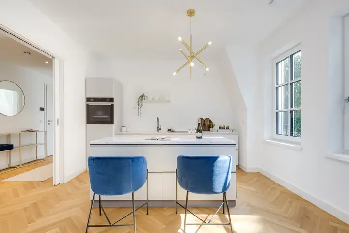 Offene Küche mit Kochinsel und blauen Barhockern in einem Neubau