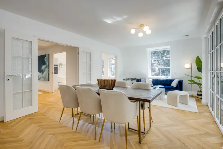 Esstisch mit hellen Stühlen und Wohnbereich in einer Maisonette