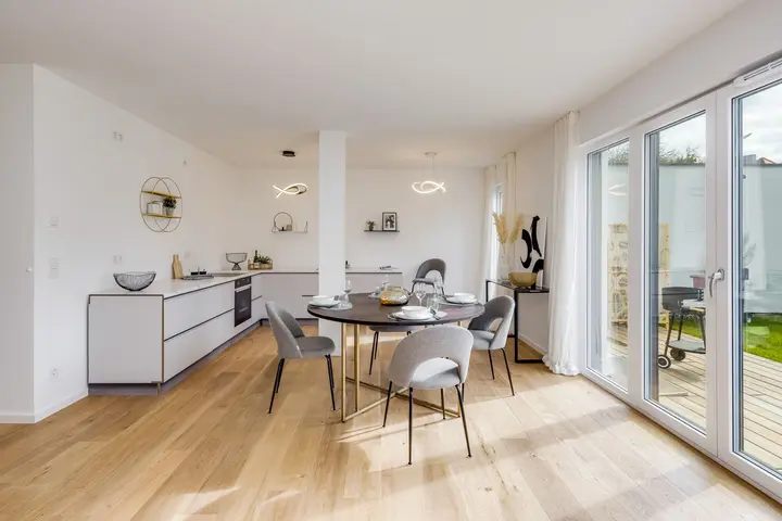 Offene Wohnküche mit Esstisch und Terrassentür in einem Musterhaus