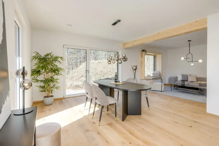 Wohn- und Essbereich mit Holzbalken und Pflanze in einem Neubau