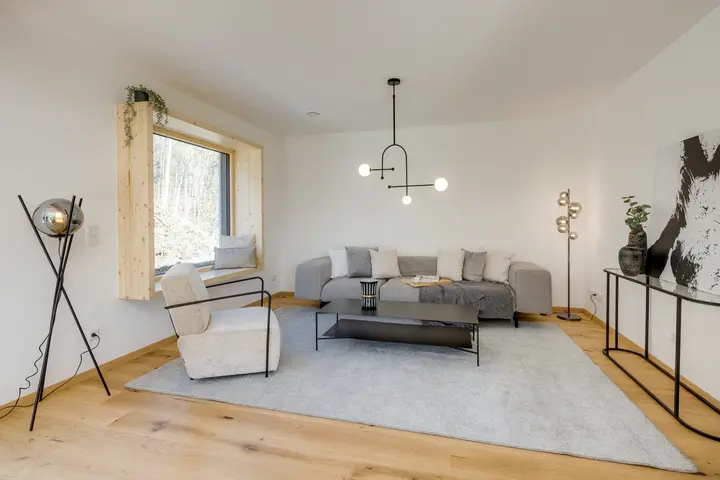 Wohnzimmer mit grauem Sofa, Couchtisch und Stehleuchten in einem Musterhaus