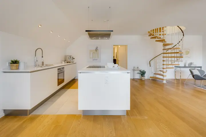 Kücheninsel und Wendeltreppe in einer Dachgeschosswohnung