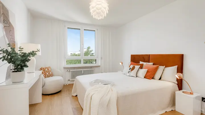 Schlafzimmer mit orangefarbenem Kopfteil und Leuchte