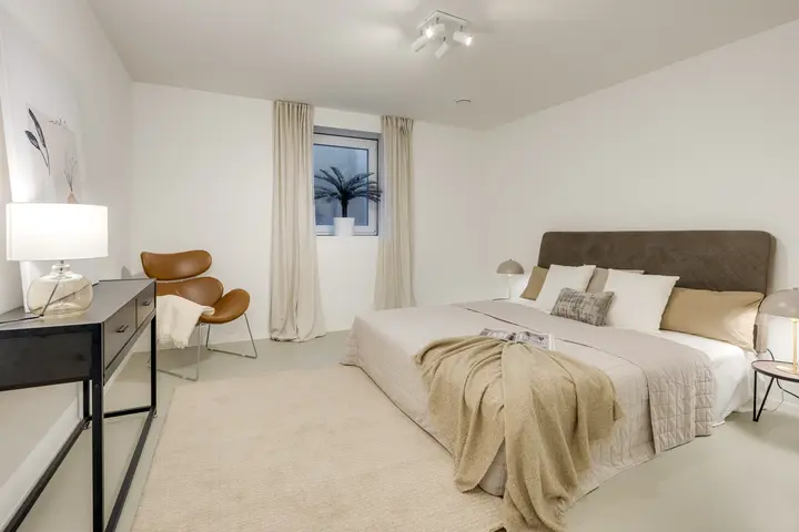 Schlafzimmer mit Doppelbett und Sessel nach dem Home Staging