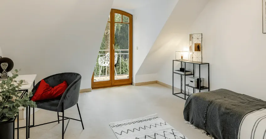 Schlafzimmer mit Holzbalken nach dem Home Staging mit Bett, Sessel und Pflanze