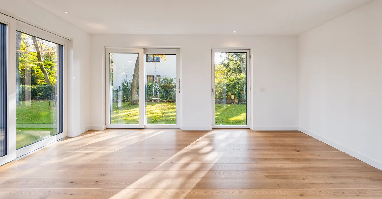 Leeres Wohnzimmer mit Fensterfront zum Garten vor dem Home Staging