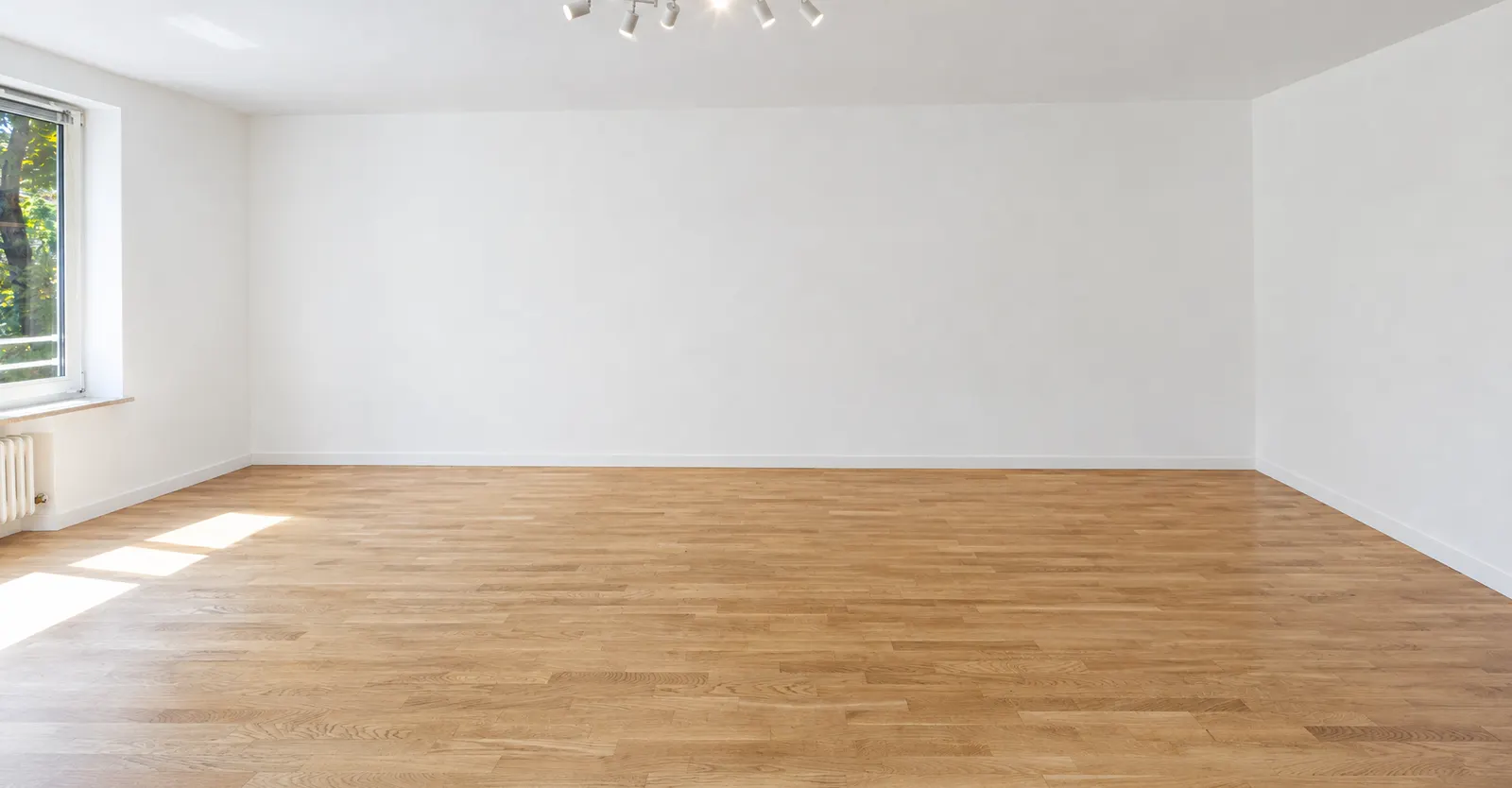 Leerer Wohnraum mit Parkett und Fenster vor dem Home Staging